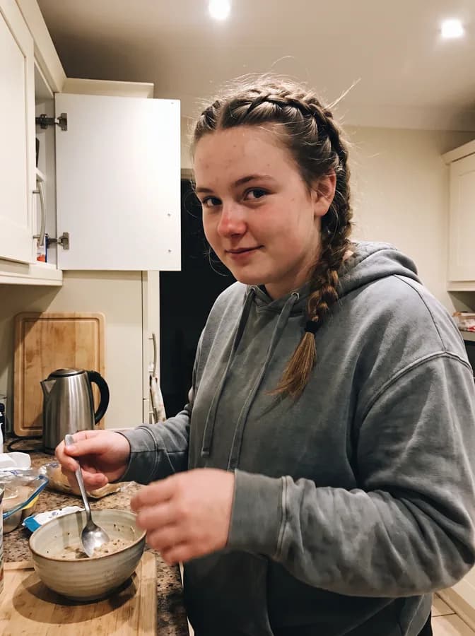 One of the phone photos a parent sent: a fictional softball player at the kitchen counter at home in a hoodie; photo generated