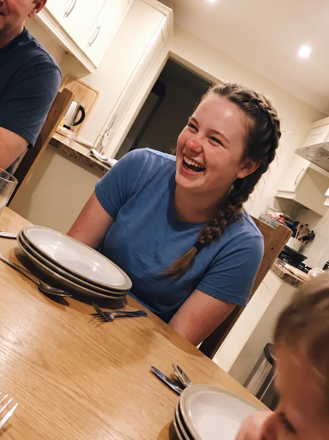 One of the phone photos a parent sent: a fictional softball player laughing at the kitchen table at home; photo generated