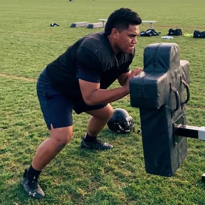 Example of a photo to send: a fictional football player seen head to shoes, pushing a blocking sled — generated example photo