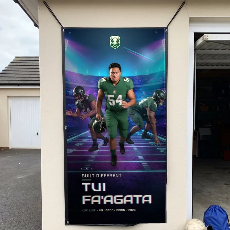 A custom football banner hanging by cords from its corner grommets on the outside wall of a garage — Prism Rush finish — example artwork, fictional roster athlete; photo generated