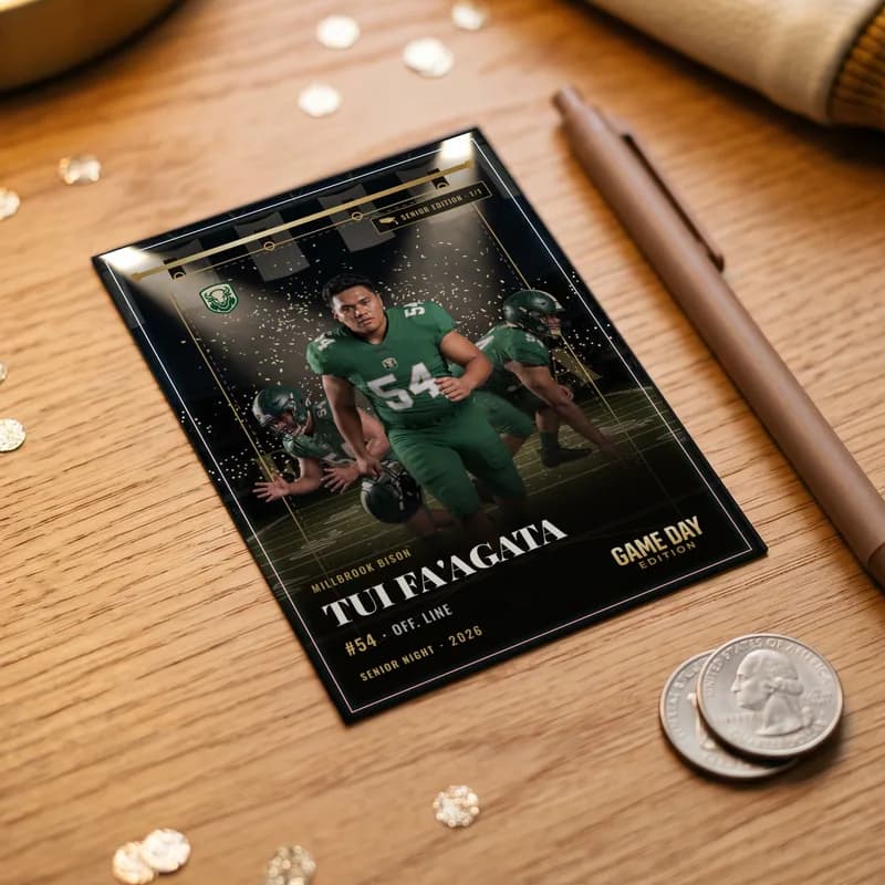 A custom football trading card lying on a wooden desk beside a pen and two coins, for scale — Senior Night finish — example artwork, fictional roster athlete; photo generated