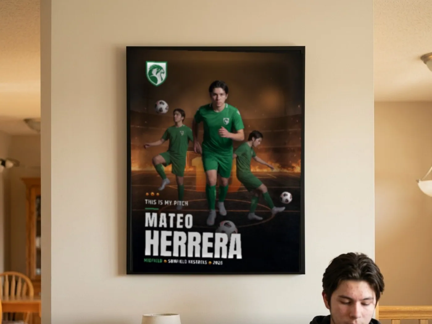 A framed custom soccer poster on a living-room wall above the sofa where the athlete is sitting — example artwork, fictional roster athlete; photo generated