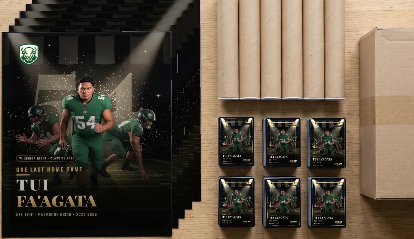 A whole-class team order laid out on a table: a stack of custom football posters, a row of shipping tubes, stacks of trading cards and the box they ship in — Senior Night finish — example artwork, fictional roster athlete; photo generated
